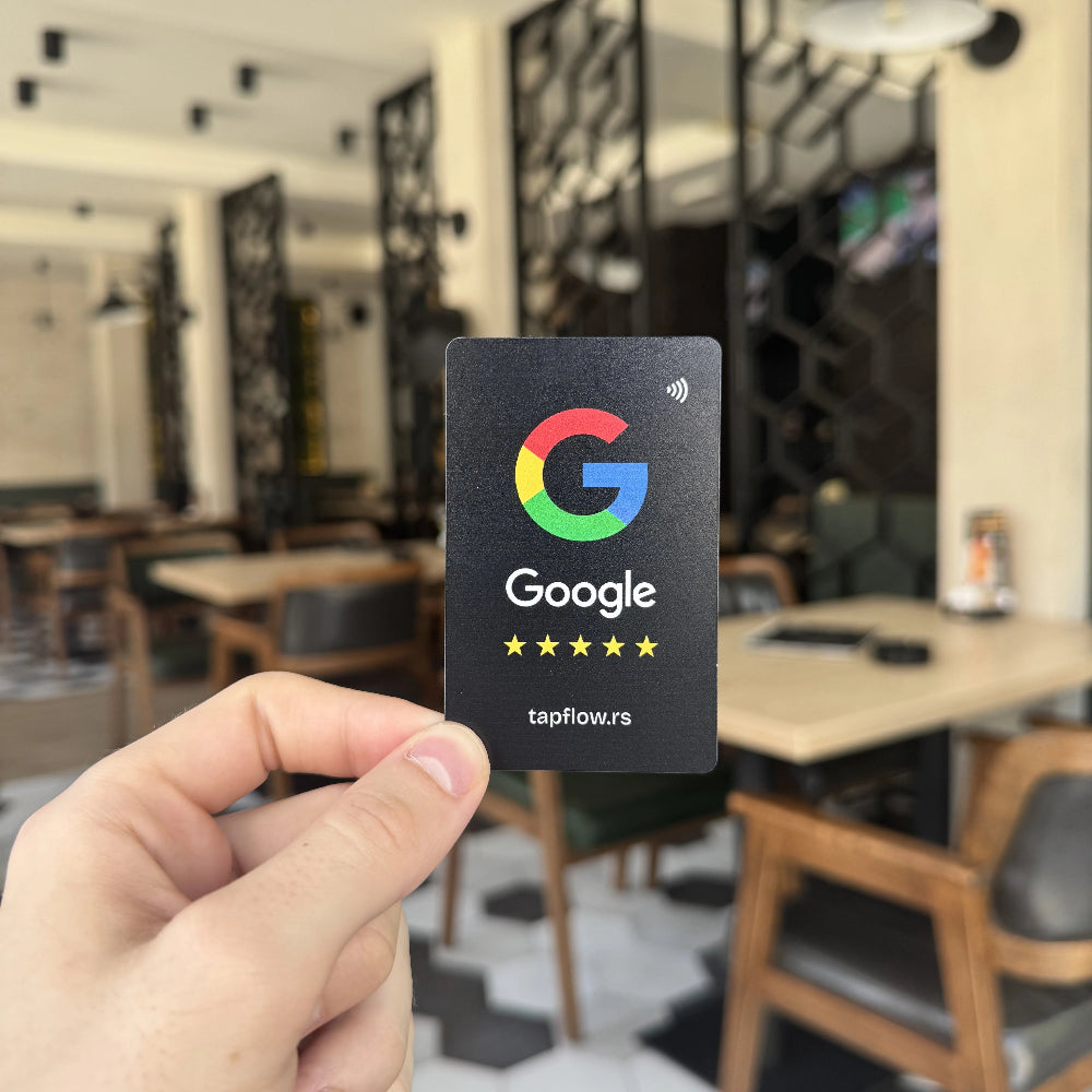 Hand holding a Google gift card in an indoor setting with tables and chairs.